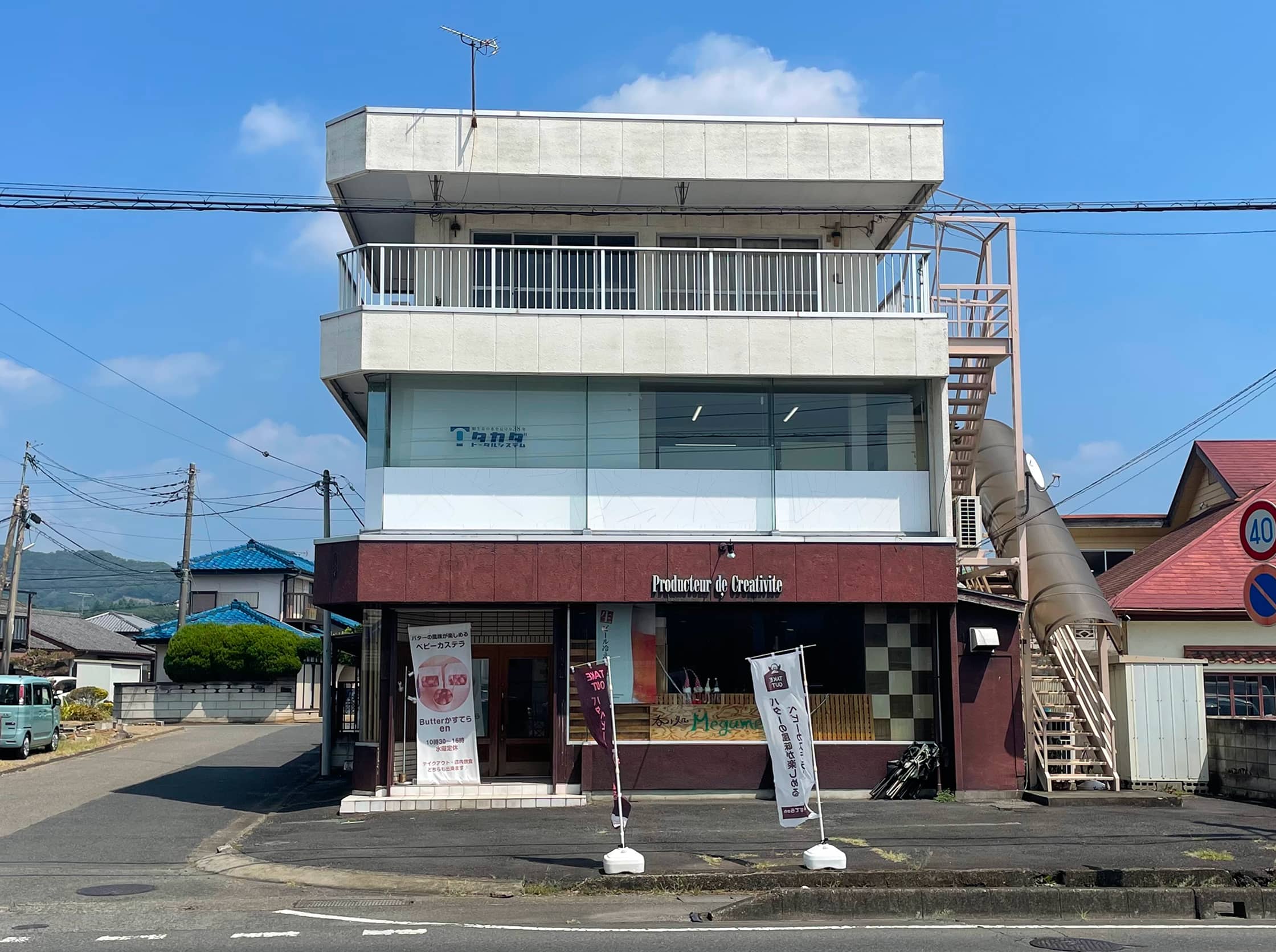 街路樹と電線が並ぶ通りに面したオフィスビル。