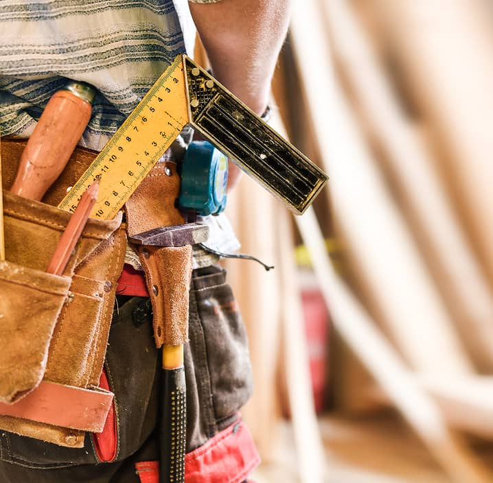 ツールベルトに工具や定規を差し込んだ大工の腰元のクローズアップ