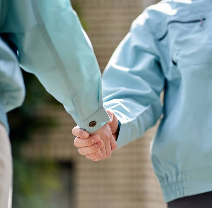 作業服を着た2人が手を取り合って信頼を示す様子