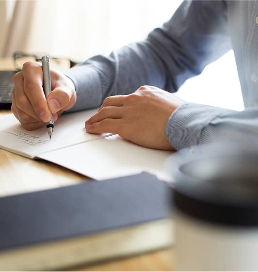 ノートにペンで文字を書き込んでいる手元の様子