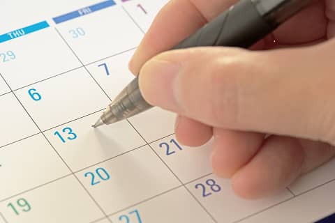 カレンダーに予定を書き込もうとする手元のクローズアップ