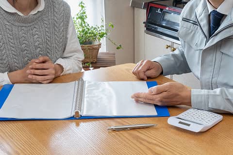 テーブル上の資料を見ながら説明する作業員と相談者