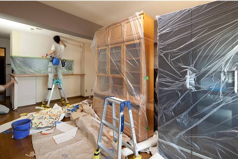 室内の壁をリフォーム中で、家具がビニールで覆われている様子