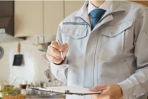 作業着を着た男性がクリップボードにメモを取りながら説明する様子