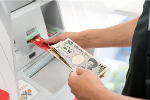 ATMでキャッシュカードを挿入しながら現金を引き出す手元