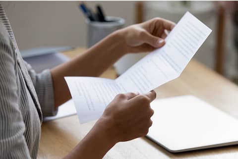 両手で書類を持ち、内容を読んでいる女性の手元