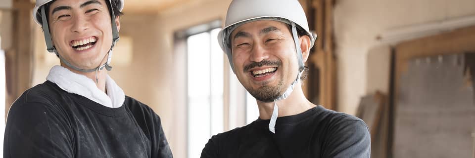 建築現場で笑顔を見せるヘルメット姿の2人の作業員