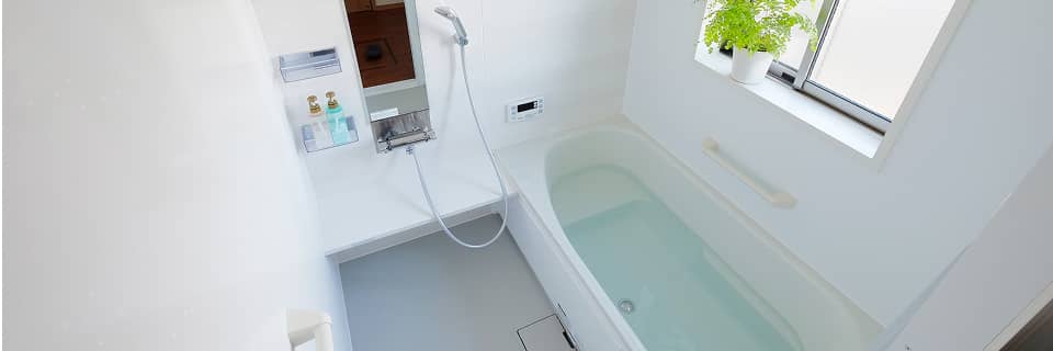 窓付きで明るい浴室と白いバスタブの様子