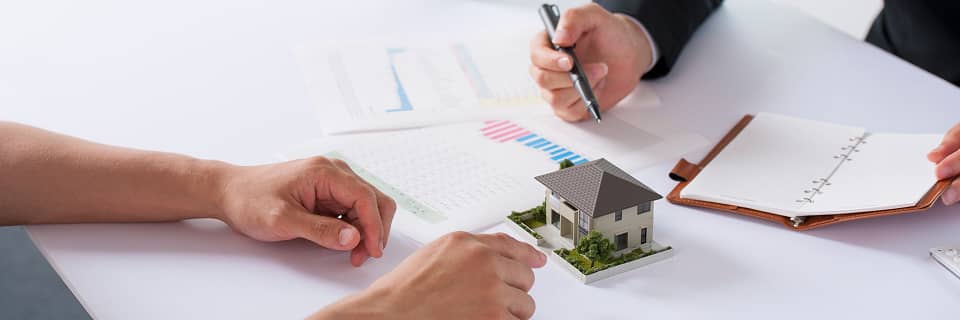 住宅模型とグラフ資料を見ながら相談する不動産打ち合わせ