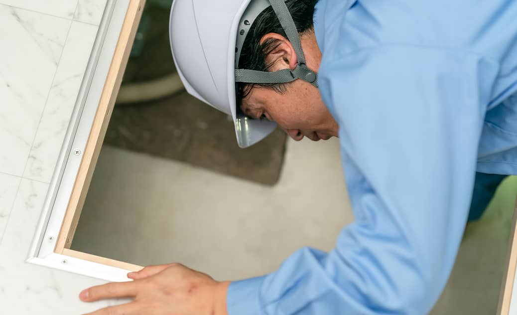 ヘルメットを着用した作業員が床下収納を開けて点検している様子